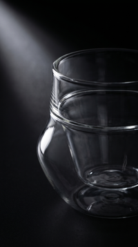 Empty Double-Wall Glass in wide view against matte charcoal