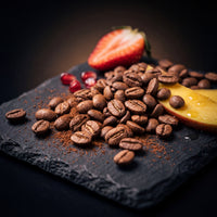 Colombia Papayo Jungle Reserve tasting-note still life — roasted beans with strawberry, pomegranate seeds and mango on slate